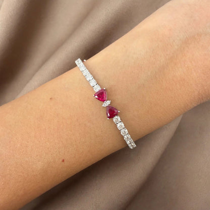 Natural ruby and diamond bow tennis bracelet in 18K white gold worn on wrist
