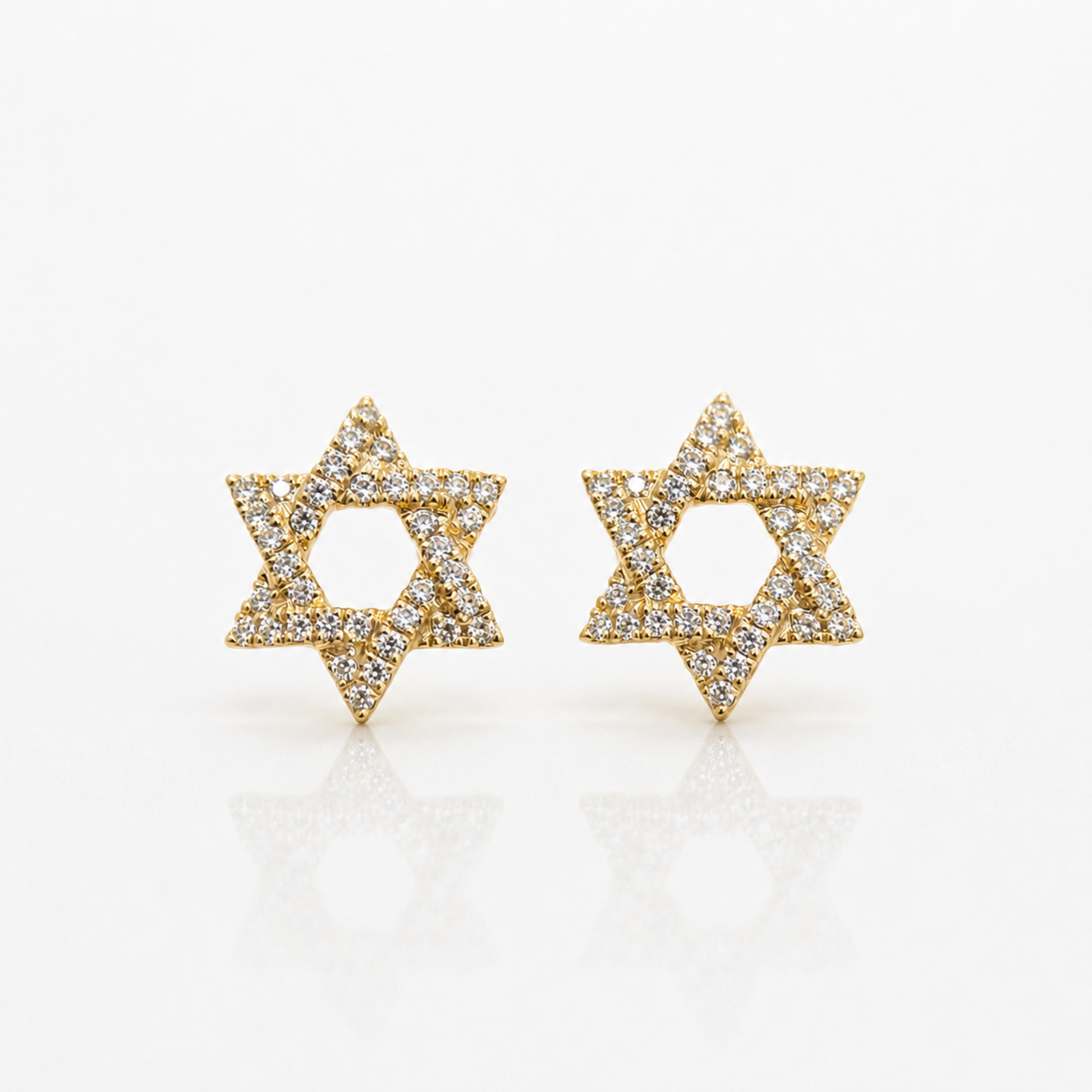 A pair of gold Star of David stud earrings paved with small clear diamonds, displayed on a clean white reflective surface.
