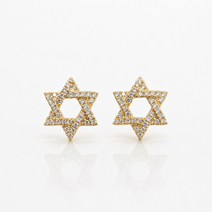 A pair of gold Star of David stud earrings paved with small clear diamonds, displayed on a clean white reflective surface.