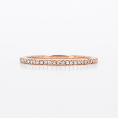 A thin rose gold eternity ring paved with small round-cut diamonds, shown on a clean white background with a soft reflection.