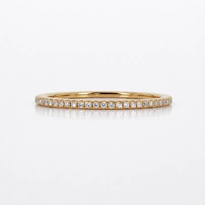 A thin yellow gold eternity ring paved with small round-cut diamonds, displayed on a clean white reflective surface.