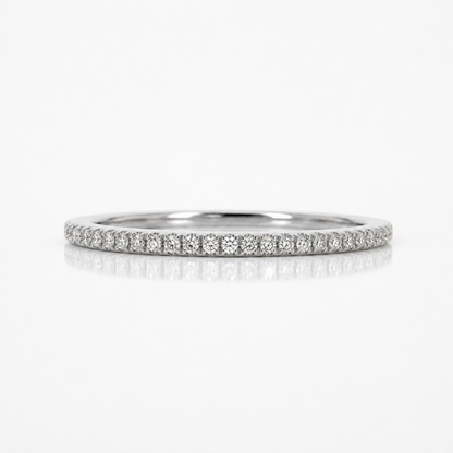 A thin diamond eternity band ring in silver-colored metal, featuring a continuous row of small round-cut diamonds set in a pave style, shown on a clean white background with a soft reflection below.