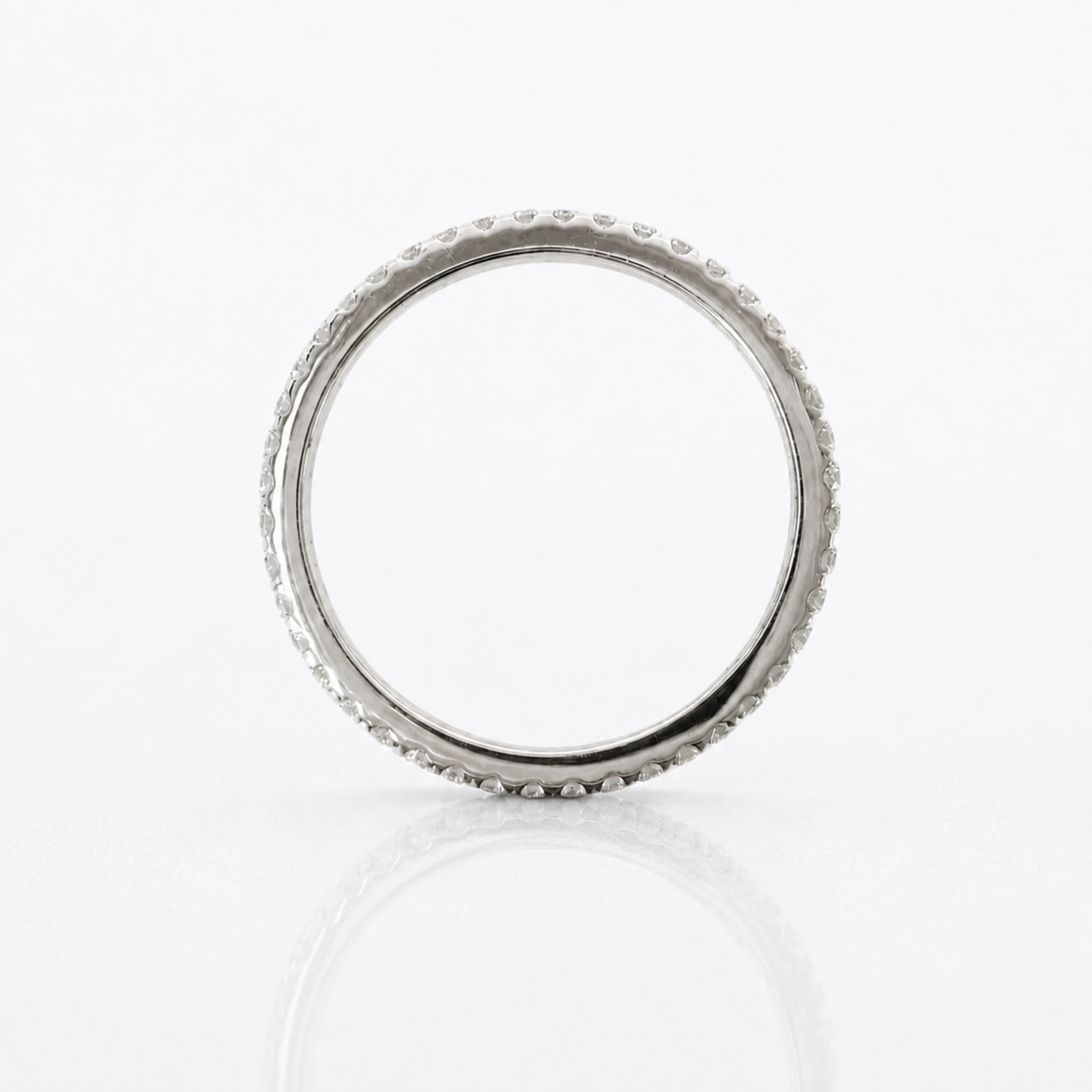 A silver band ring with a textured, beaded outer edge, photographed on a clean white reflective surface.