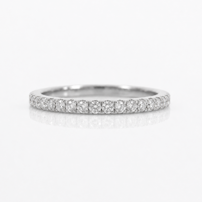 A thin diamond eternity band ring in a silver-toned metal, featuring a continuous row of round-cut diamonds set along the band, photographed on a clean white background with a soft reflection below.