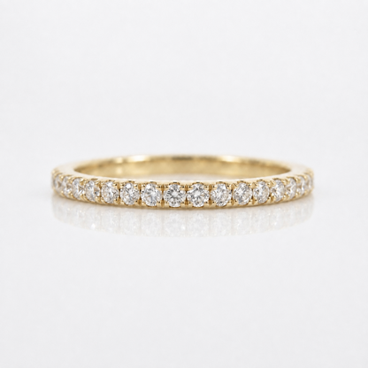 A yellow gold eternity ring set with round brilliant-cut diamonds, shown on a clean white reflective surface.