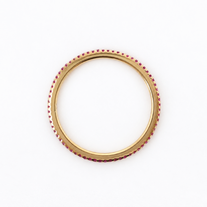 A gold ring adorned with small, evenly spaced red rubies along the outer edge, shown against a plain white background.