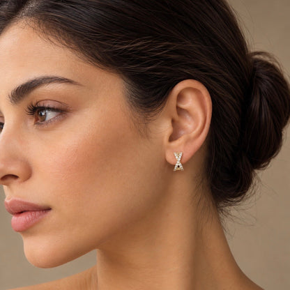 Side profile of a model wearing 14K yellow gold natural diamond X huggie earrings.