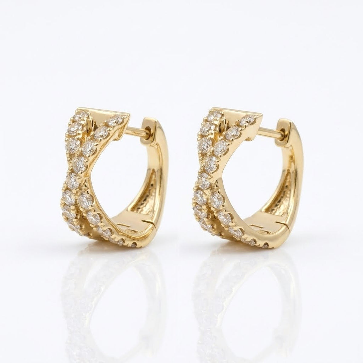 Side view of 14K yellow gold natural diamond X huggie hoop earrings showing the curved hoop design and diamond settings.